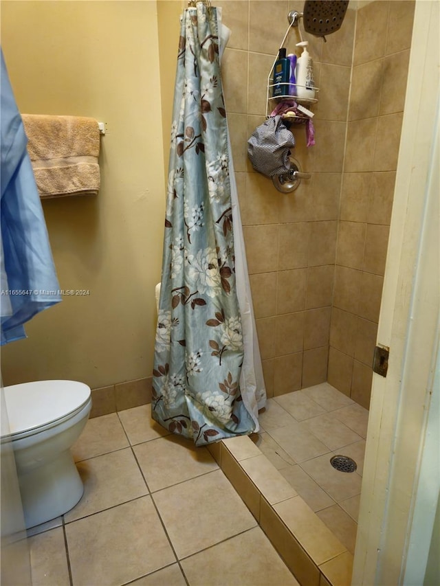 bathroom with a shower with shower curtain, tile patterned flooring, and toilet