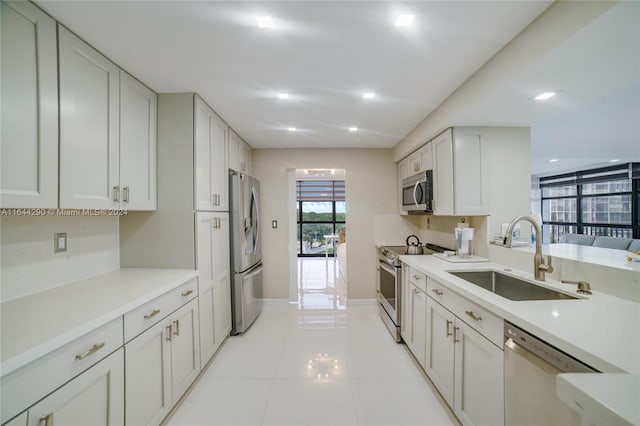 kitchen with sink, light tile patterned floors, appliances with stainless steel finishes, and white cabinetry