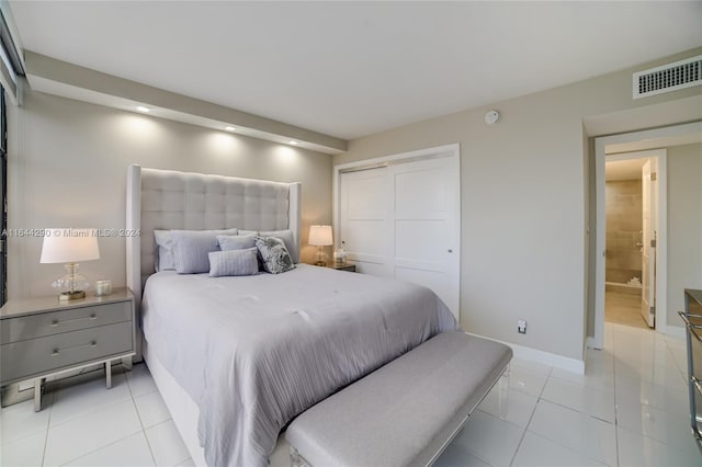 bedroom featuring light tile patterned floors, connected bathroom, and a closet