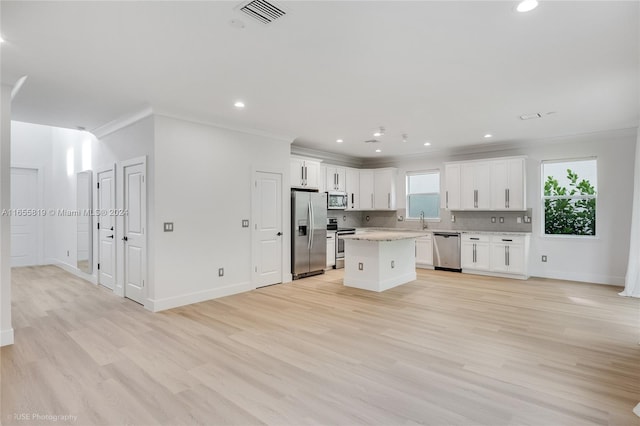 kitchen with a kitchen island, stainless steel appliances, white cabinetry, and light hardwood / wood-style flooring