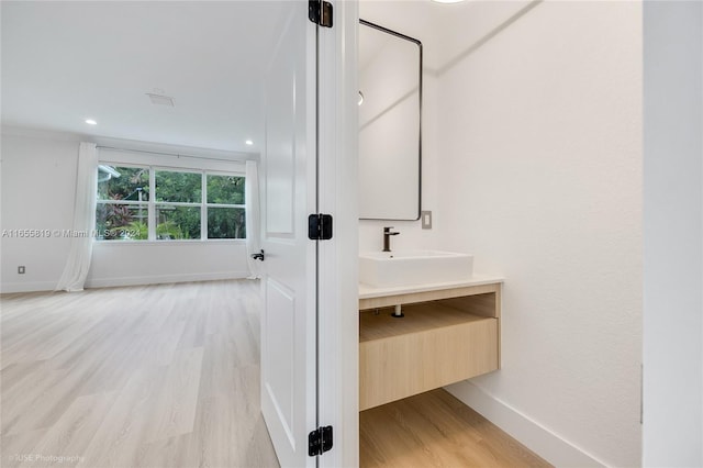 bathroom featuring recessed lighting, baseboards, wood finished floors, and vanity