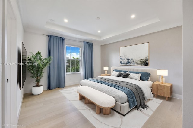 bedroom with recessed lighting, baseboards, light wood-style floors, and a tray ceiling