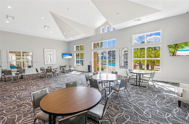 carpeted dining space with baseboards, visible vents, and high vaulted ceiling