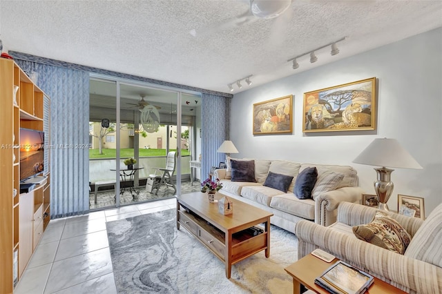 living room featuring track lighting, ceiling fan, and a textured ceiling