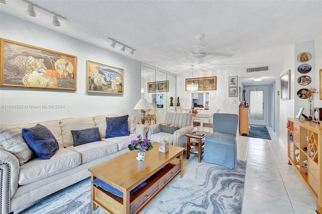 tiled living room featuring a textured ceiling, rail lighting, and ceiling fan