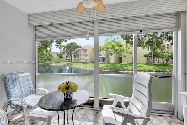 sunroom / solarium with a water view, ceiling fan, and a wealth of natural light