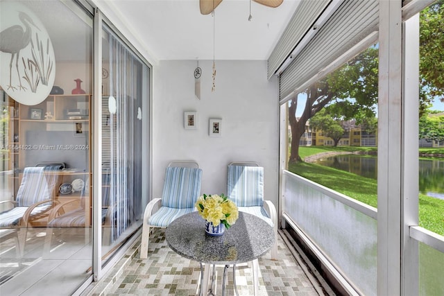 sunroom with a water view and ceiling fan