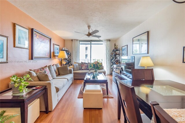 living room with light wood-type flooring, a textured ceiling, and ceiling fan