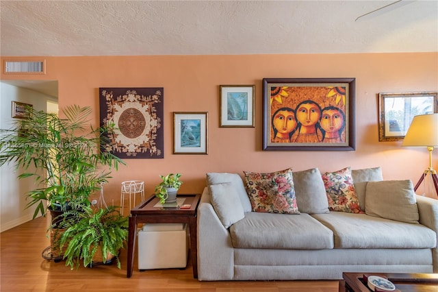 living room featuring light wood-type flooring and a textured ceiling