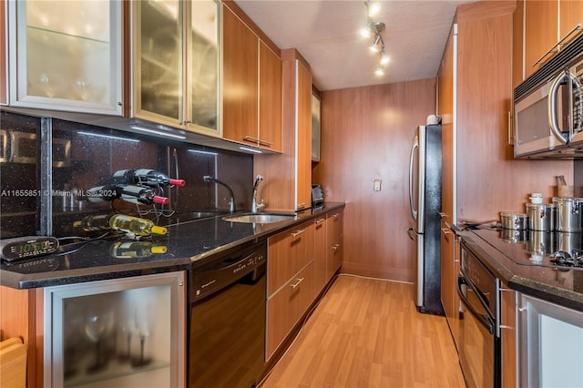 kitchen featuring black appliances, light hardwood / wood-style flooring, sink, and dark stone counters