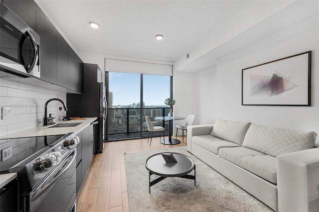 living room featuring floor to ceiling windows, light wood-style flooring, and recessed lighting