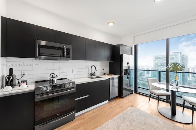 kitchen featuring decorative backsplash, dark cabinetry, appliances with stainless steel finishes, and a sink