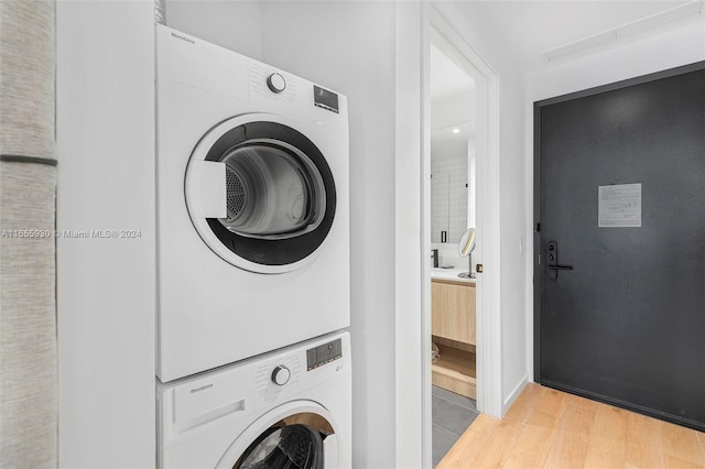 washroom featuring light wood finished floors, stacked washer / dryer, and laundry area