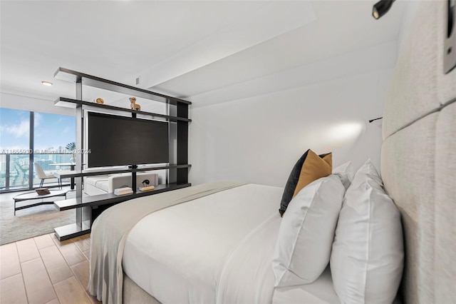 bedroom with a wall of windows and wood finished floors