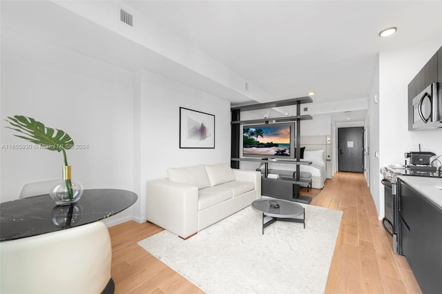 living area with recessed lighting, visible vents, light wood-type flooring, and baseboards