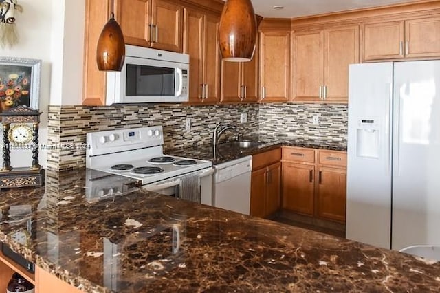 kitchen with white appliances, backsplash, dark stone counters, and sink