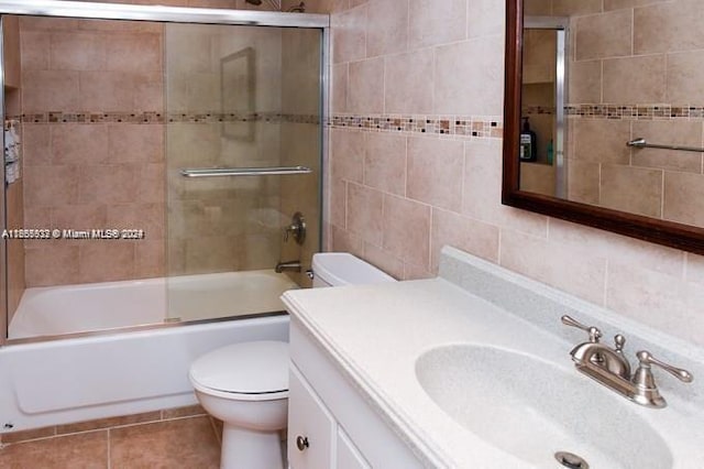 full bathroom with vanity, tile walls, toilet, tile patterned floors, and enclosed tub / shower combo