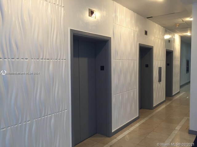 hall featuring elevator and light tile patterned floors