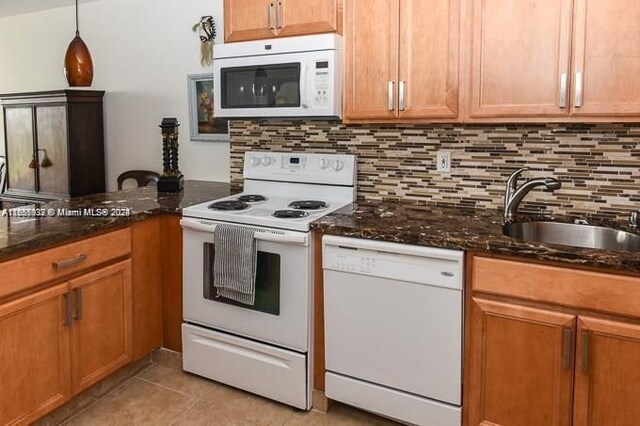 kitchen with dark stone counters, white appliances, and sink