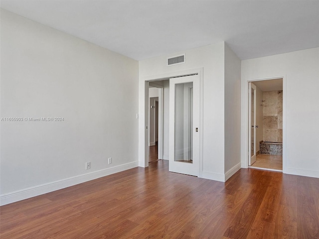 unfurnished bedroom with dark hardwood / wood-style floors and connected bathroom