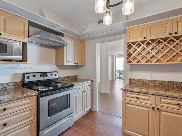 kitchen featuring appliances with stainless steel finishes, light brown cabinets, wood-type flooring, and stone counters