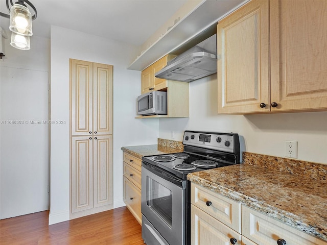 kitchen featuring light brown cabinetry, hardwood / wood-style flooring, stainless steel appliances, and wall chimney exhaust hood