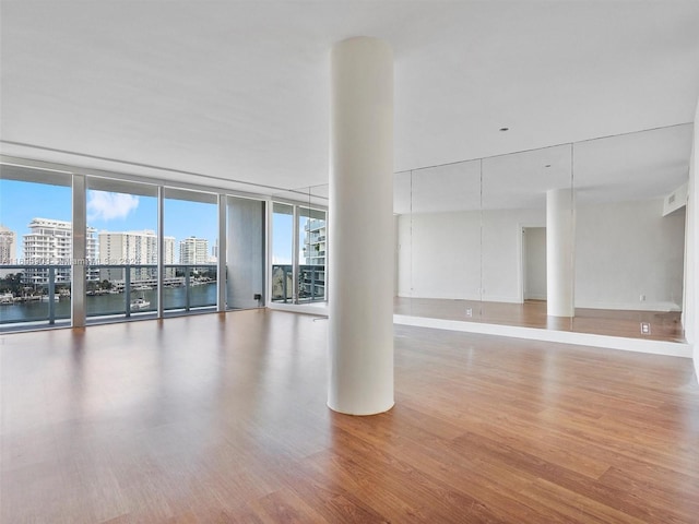 spare room featuring a water view, hardwood / wood-style floors, and floor to ceiling windows