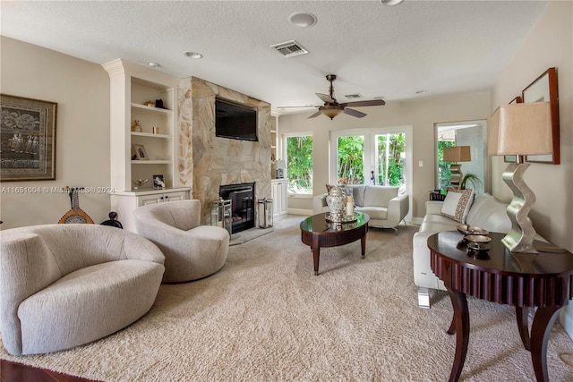 carpeted living room featuring a fireplace, a textured ceiling, and ceiling fan