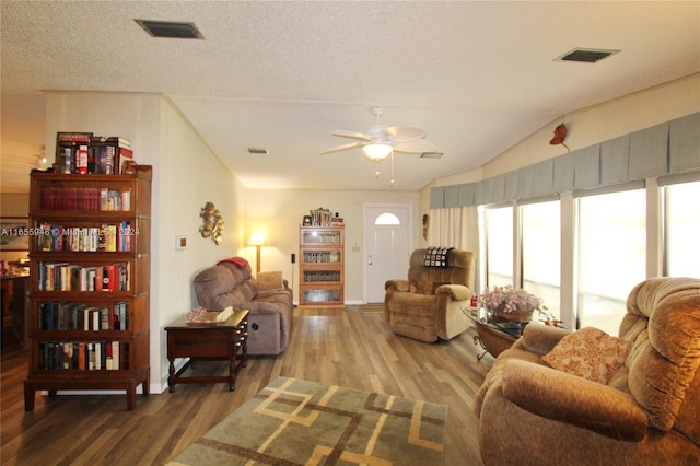 living room with ceiling fan, hardwood / wood-style flooring, vaulted ceiling, and a textured ceiling