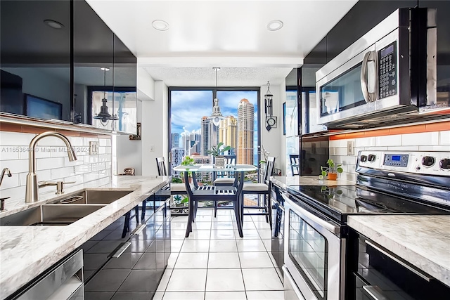 kitchen featuring decorative light fixtures, a wealth of natural light, stainless steel appliances, and sink