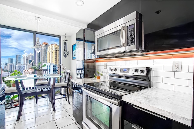 kitchen with an inviting chandelier, decorative light fixtures, stainless steel appliances, light tile patterned flooring, and tasteful backsplash