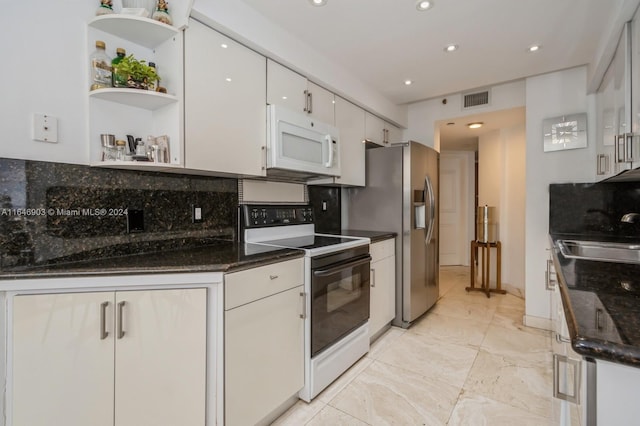 kitchen featuring dark stone counters, sink, white cabinets, decorative backsplash, and white appliances