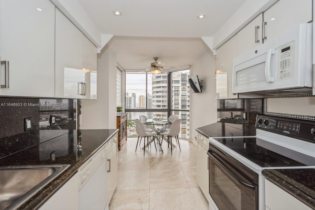 kitchen featuring white appliances, white cabinetry, dark stone countertops, and ceiling fan