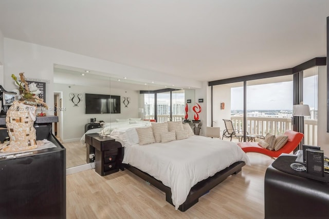 bedroom featuring a wall of windows and light hardwood / wood-style flooring