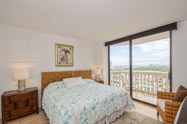 bedroom with light hardwood / wood-style flooring, expansive windows, and access to exterior