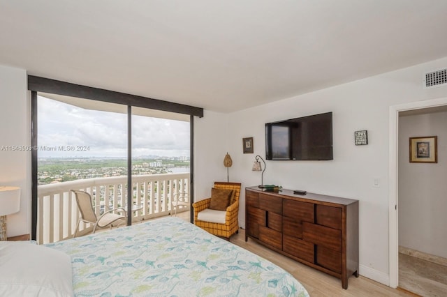 bedroom featuring light hardwood / wood-style floors, a wall of windows, and access to outside