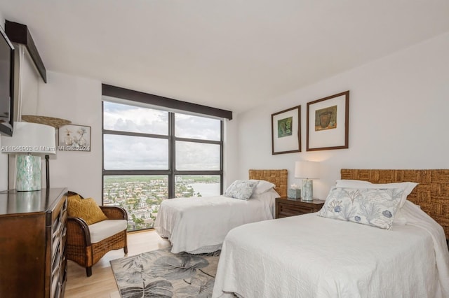 bedroom featuring light wood-type flooring and floor to ceiling windows