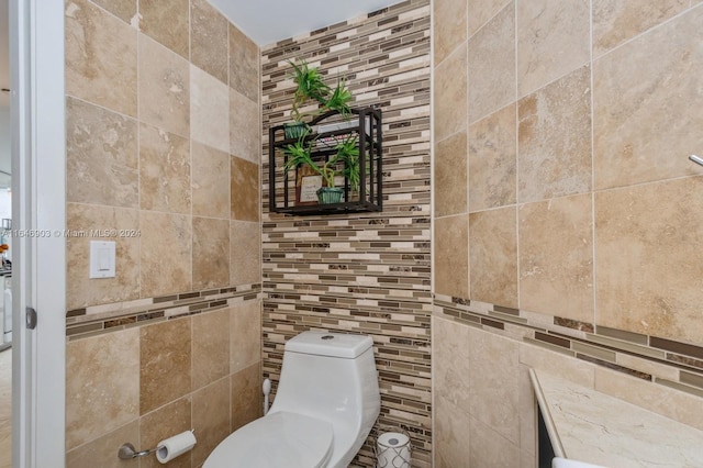 bathroom with tile walls and toilet