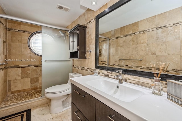 bathroom featuring tile walls, vanity, a shower with door, toilet, and tile patterned floors