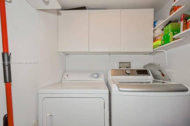 laundry room featuring separate washer and dryer and cabinets