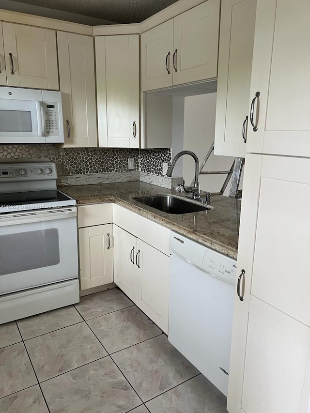 kitchen with light tile patterned floors, white appliances, sink, and tasteful backsplash