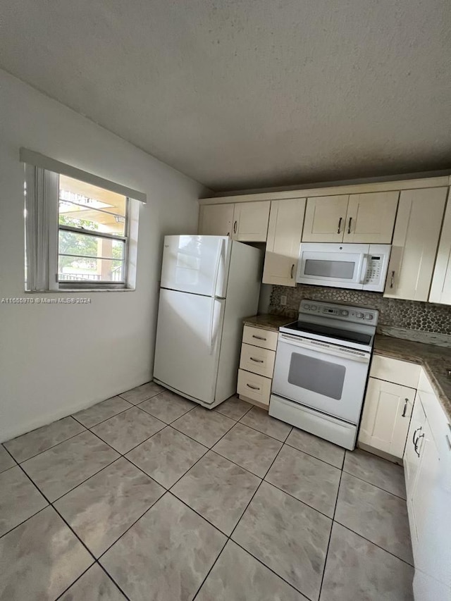 kitchen with cream cabinetry, white appliances, light tile patterned floors, and a textured ceiling