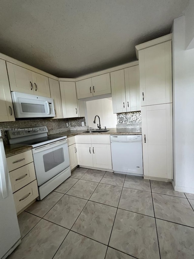 kitchen with white appliances, a textured ceiling, light tile patterned flooring, and sink