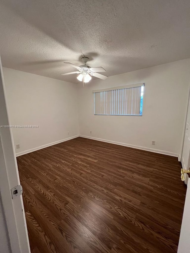 empty room featuring dark wood-type flooring, a textured ceiling, and ceiling fan