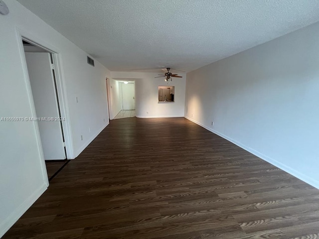 empty room with ceiling fan, dark hardwood / wood-style floors, and a textured ceiling