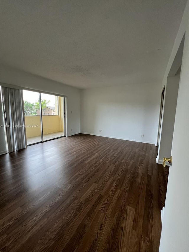 spare room featuring dark hardwood / wood-style floors and a textured ceiling