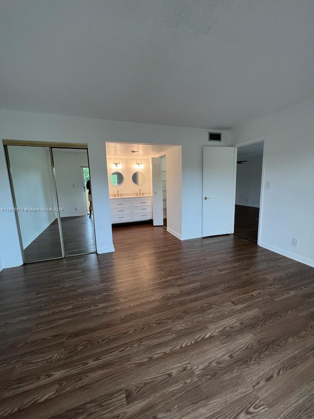 unfurnished bedroom with dark wood-type flooring and a closet