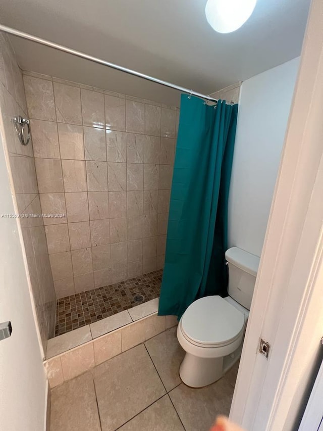 bathroom with toilet, a shower with curtain, and tile patterned floors