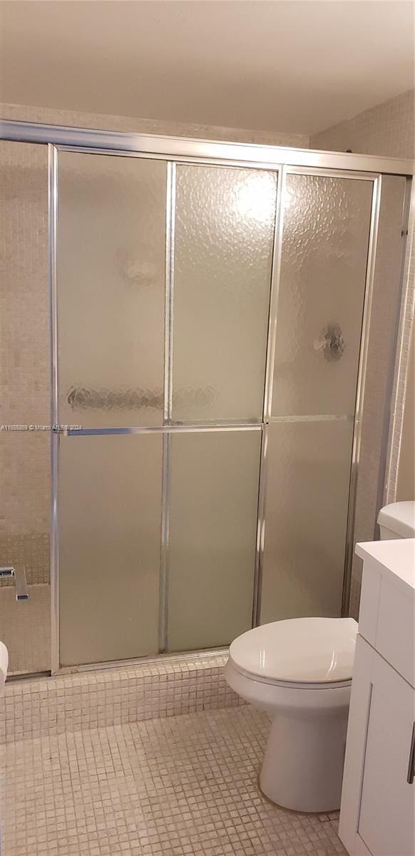 bathroom featuring vanity, toilet, a shower with shower door, and tile patterned flooring