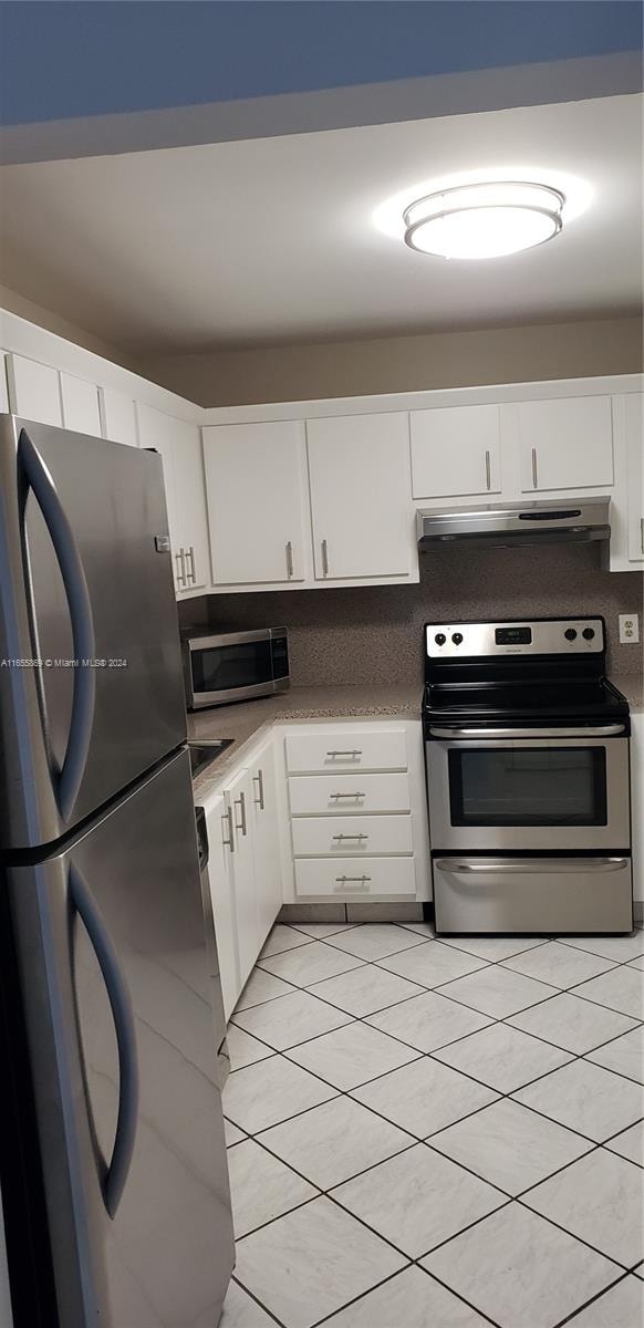 kitchen featuring white cabinets, stainless steel appliances, and light tile patterned flooring